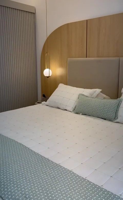 Quarto planejado pela LM Moveis com cabeceira estofada e painel em madeira